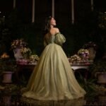A teenager in a sparkling green gown smiles during her quinceañera celebration.