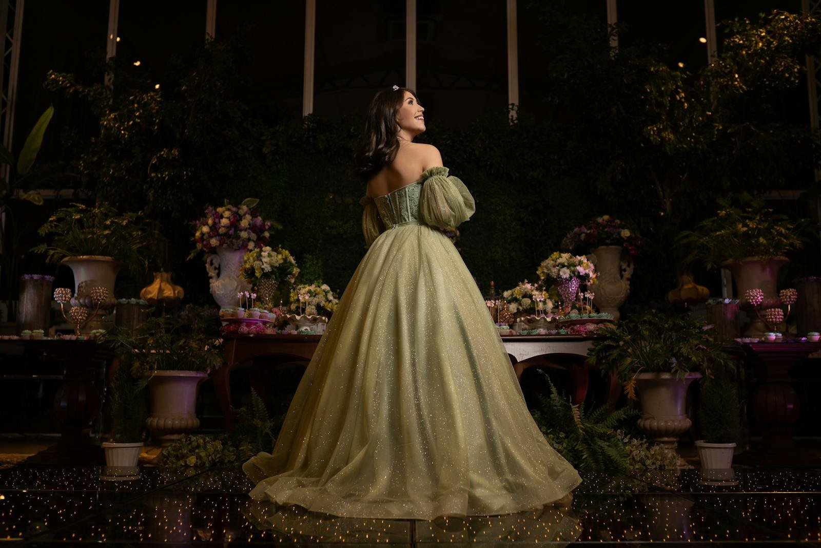 A teenager in a sparkling green gown smiles during her quinceañera celebration.