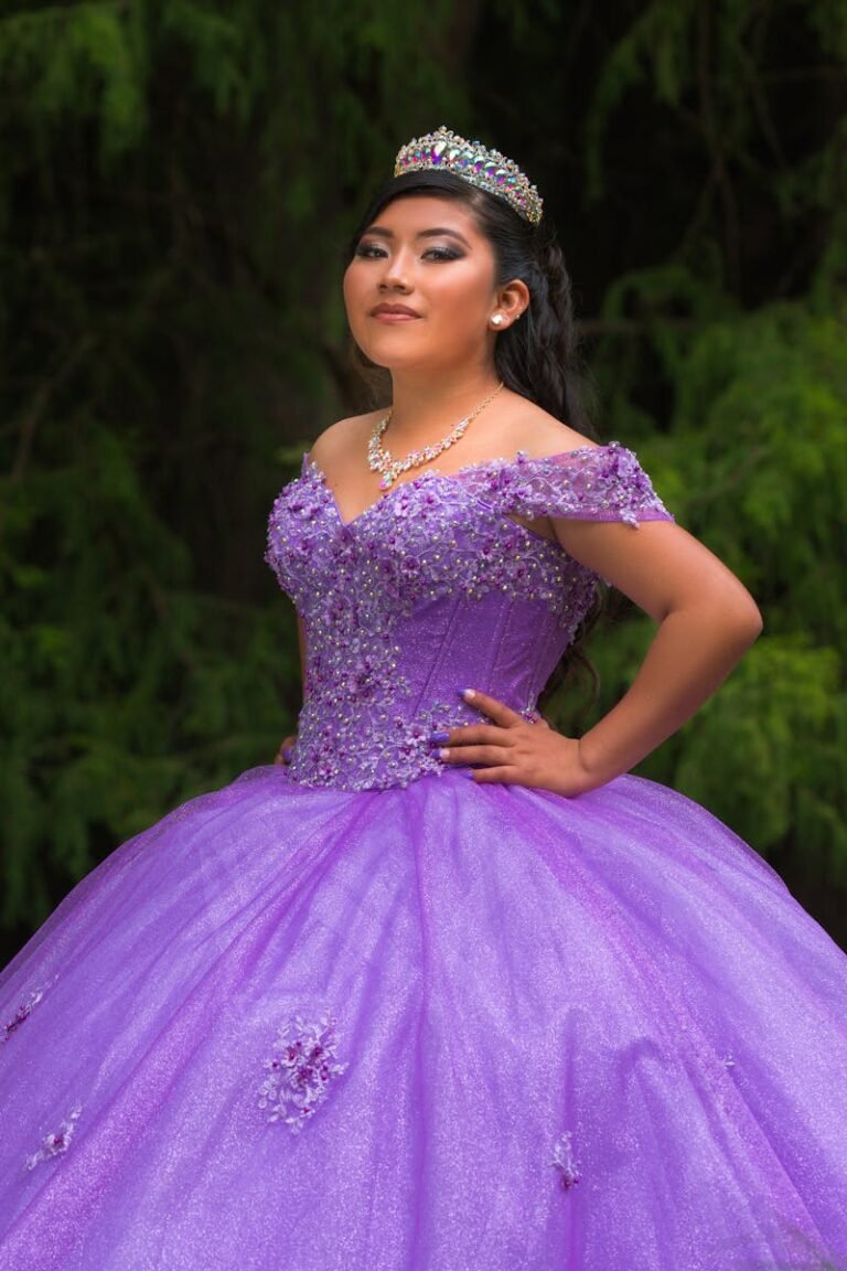 A woman elegantly posing in a detailed purple gown with a tiara, exhibiting glamour and confidence.
